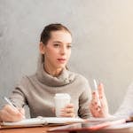 Two women engaging in a professional conversation over coffee and notes.
